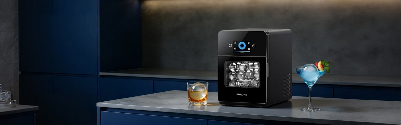 A clean countertop ice maker sits next to a cloth on a counter.
