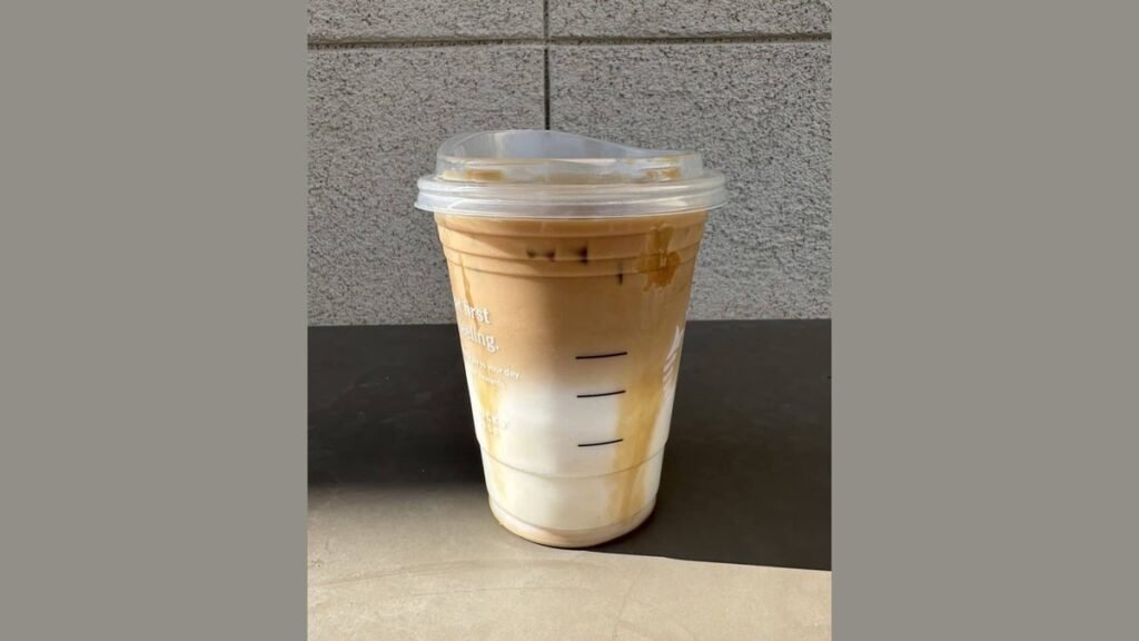 A glass of refreshing iced coffee with mint on a sunny marble table.
