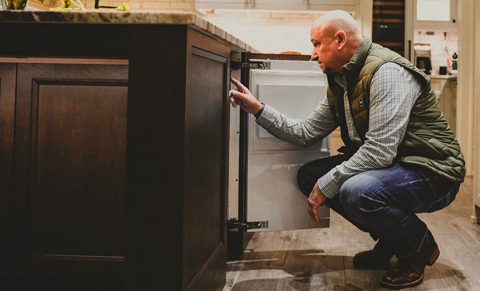 A technician performing a diagnostic check on a modern undercounter ice maker.