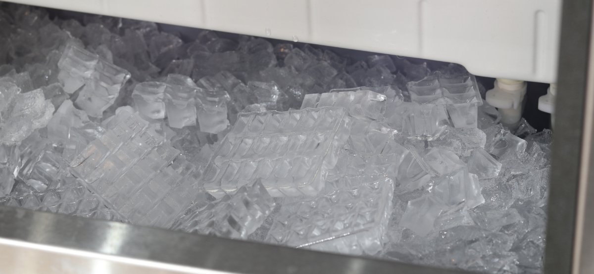 A technician's tools and service manual next to a modern commercial ice machine.