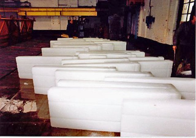 Crystal clear ice cubes move along a stainless steel conveyor in a commercial factory.