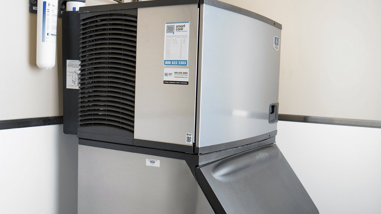 A maintenance worker cleaning the internal parts of a commercial ice machine.