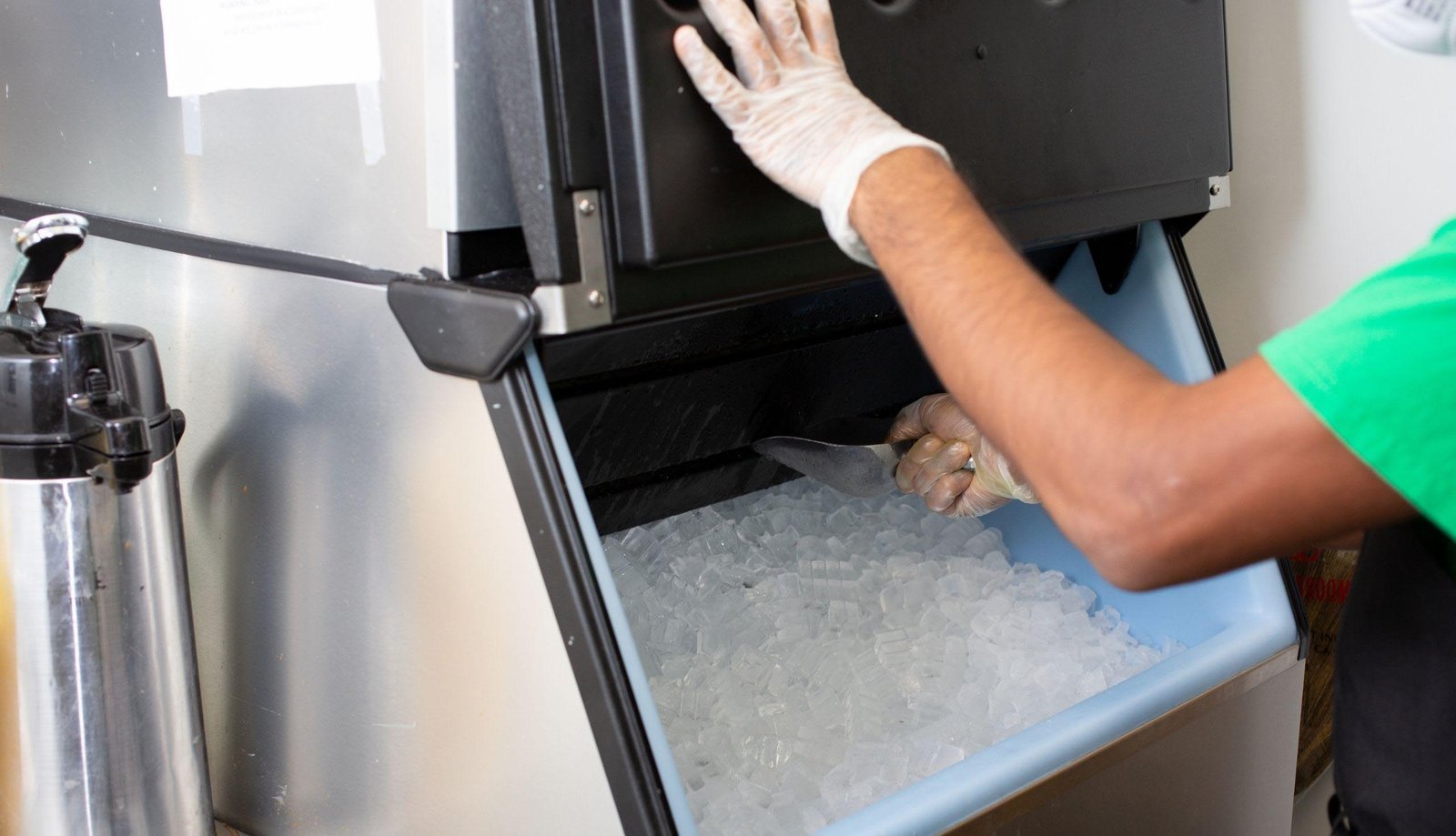 A technician measures the space around a commercial ice machine for proper installation.