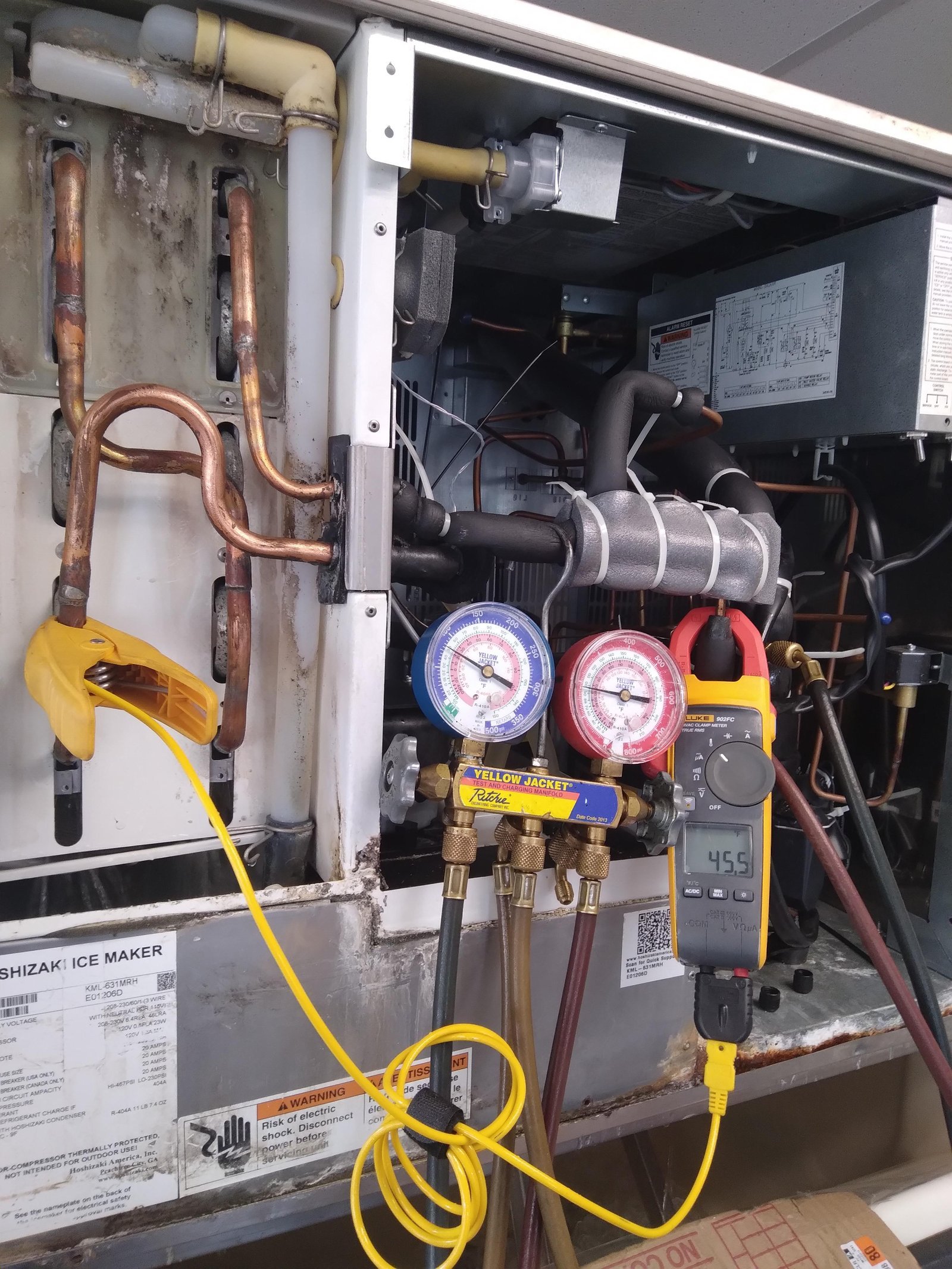 Manifold gauges connected to an ice machine for diagnostic pressure testing and troubleshooting.