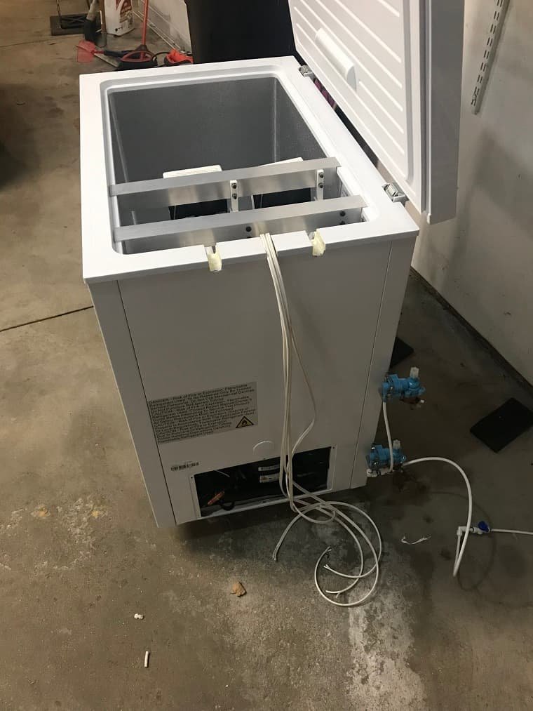 Placing a container of water into a chest freezer to make ice.
