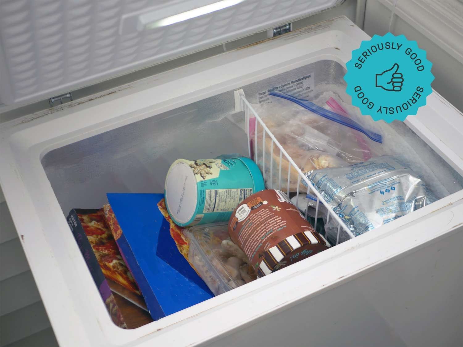 Hands checking a container of ice inside a chest freezer.