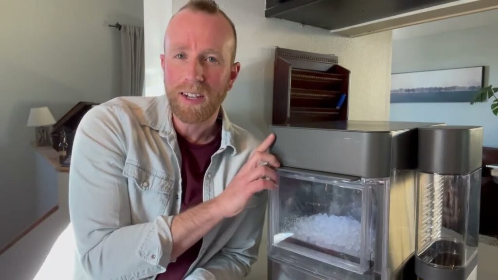 A modern GE nugget ice maker sitting on a marble kitchen countertop.