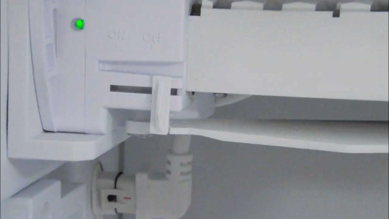 A person adjusting the wire lever on a freezer ice maker to turn it on.