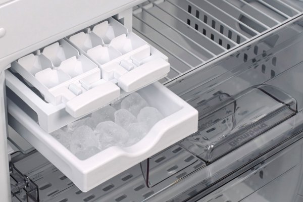 Hands adjusting an ice bin inside a clean and well-lit freezer.