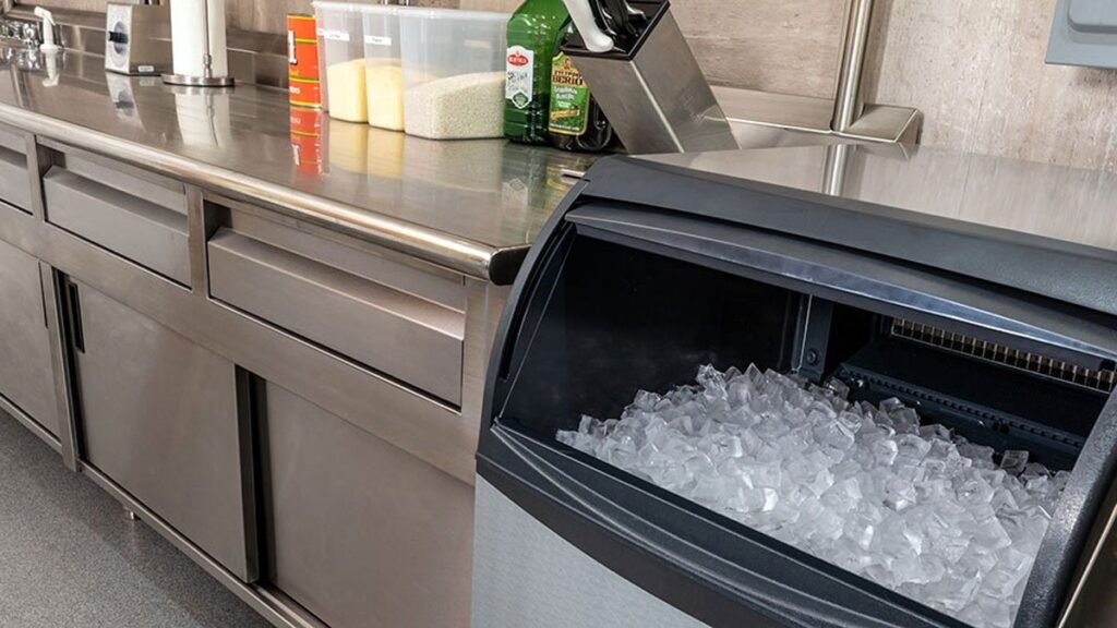 A modern stainless steel ice machine sitting on a clean kitchen countertop.