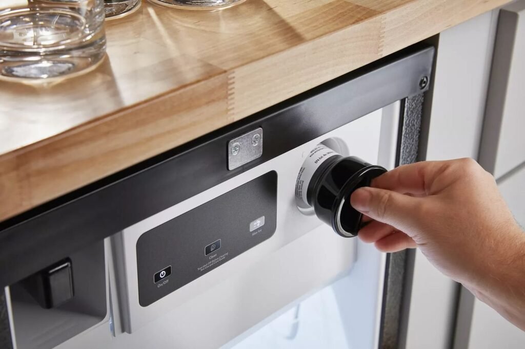 A modern stainless steel under-counter ice maker installed in a luxury kitchen island.