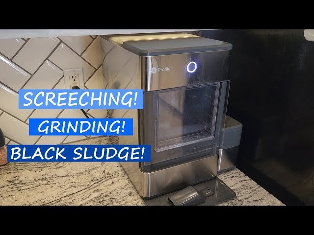 A modern GE nugget ice maker sitting on a marble kitchen countertop.