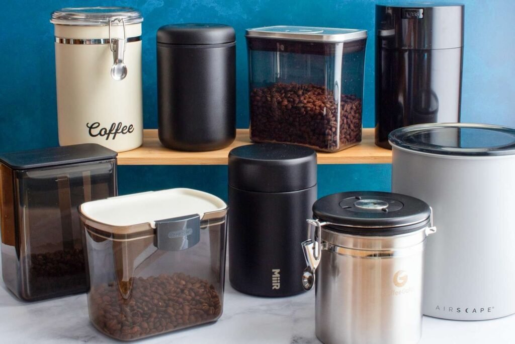 Airtight canisters and glass jars holding roasted coffee beans on an oak countertop.