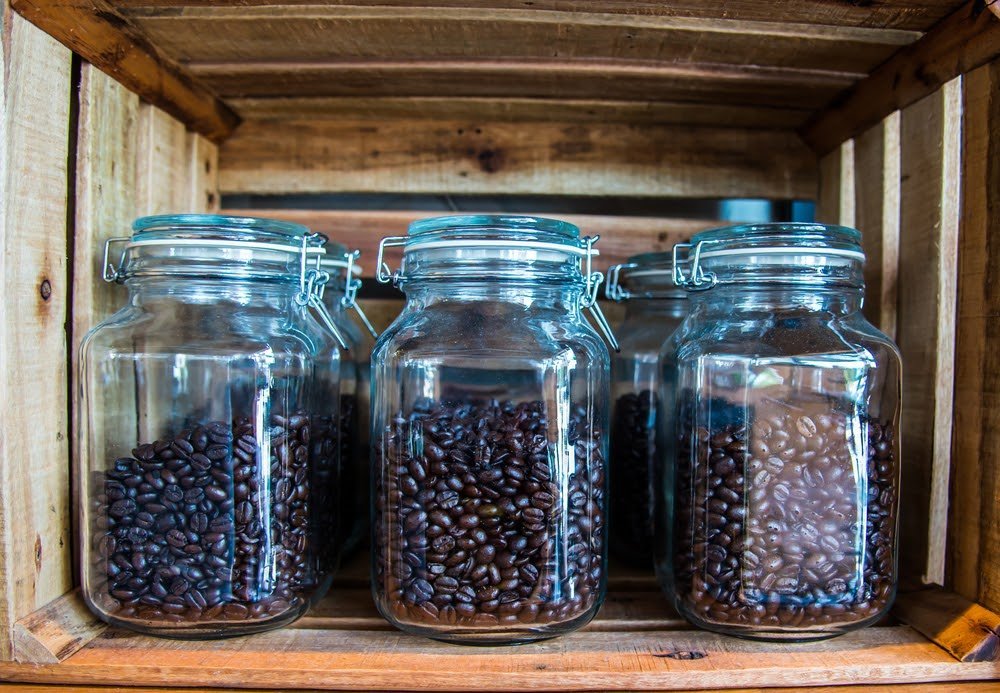 Airtight coffee canister with whole beans on oak counter in soft natural light