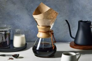 Curated Christmas coffee gifts displayed on wooden table with steaming mug