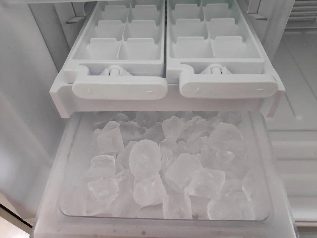 An empty ice bin inside a clean freezer ready for new ice production.