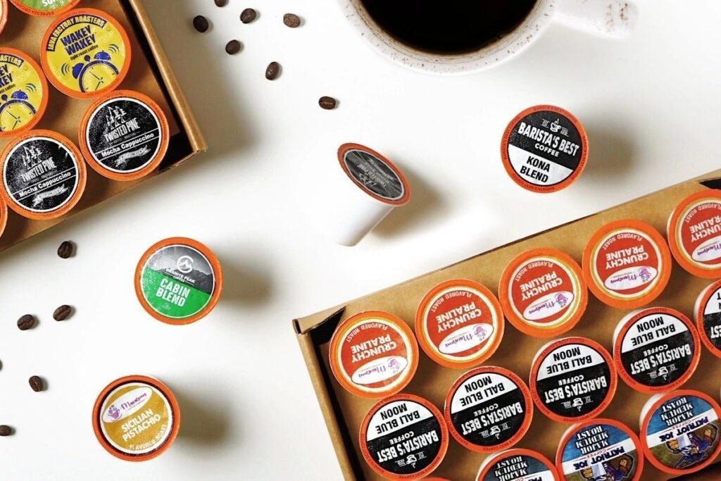Glass canisters filled with various bulk coffee beans sit on a wooden kitchen counter.