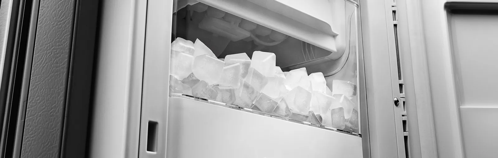 Kinked water supply tube pinched flat behind a refrigerator on a hardwood floor.