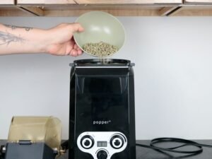 Raw green coffee beans placed beside roasted beans for home roasting preparation.