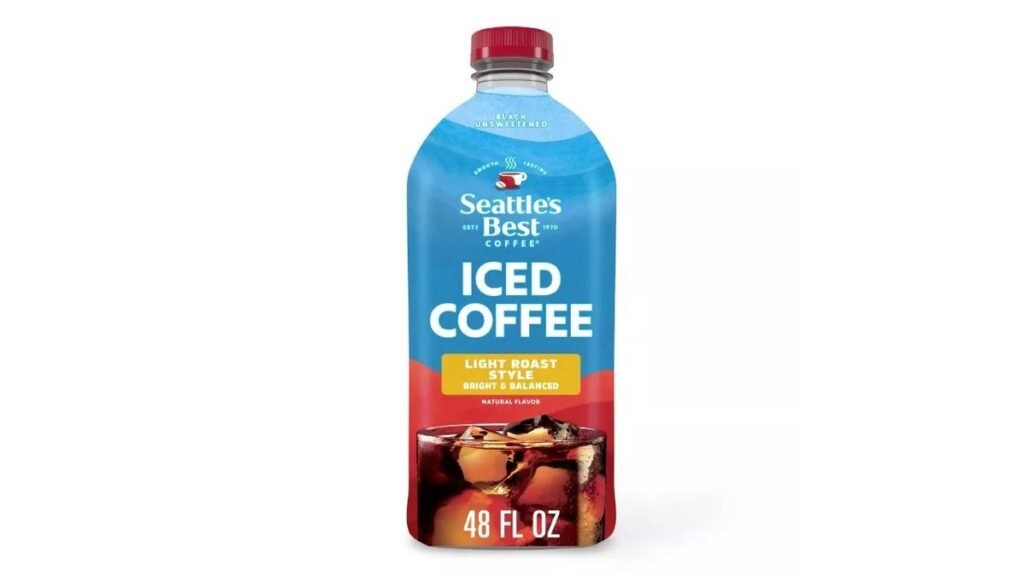A tall glass of iced coffee next to roasted coffee beans.