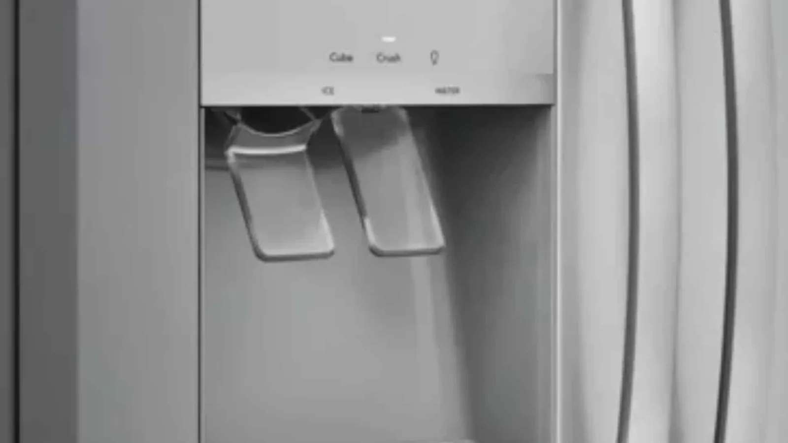 Technician kneeling beside a refrigerator to inspect a water leak.